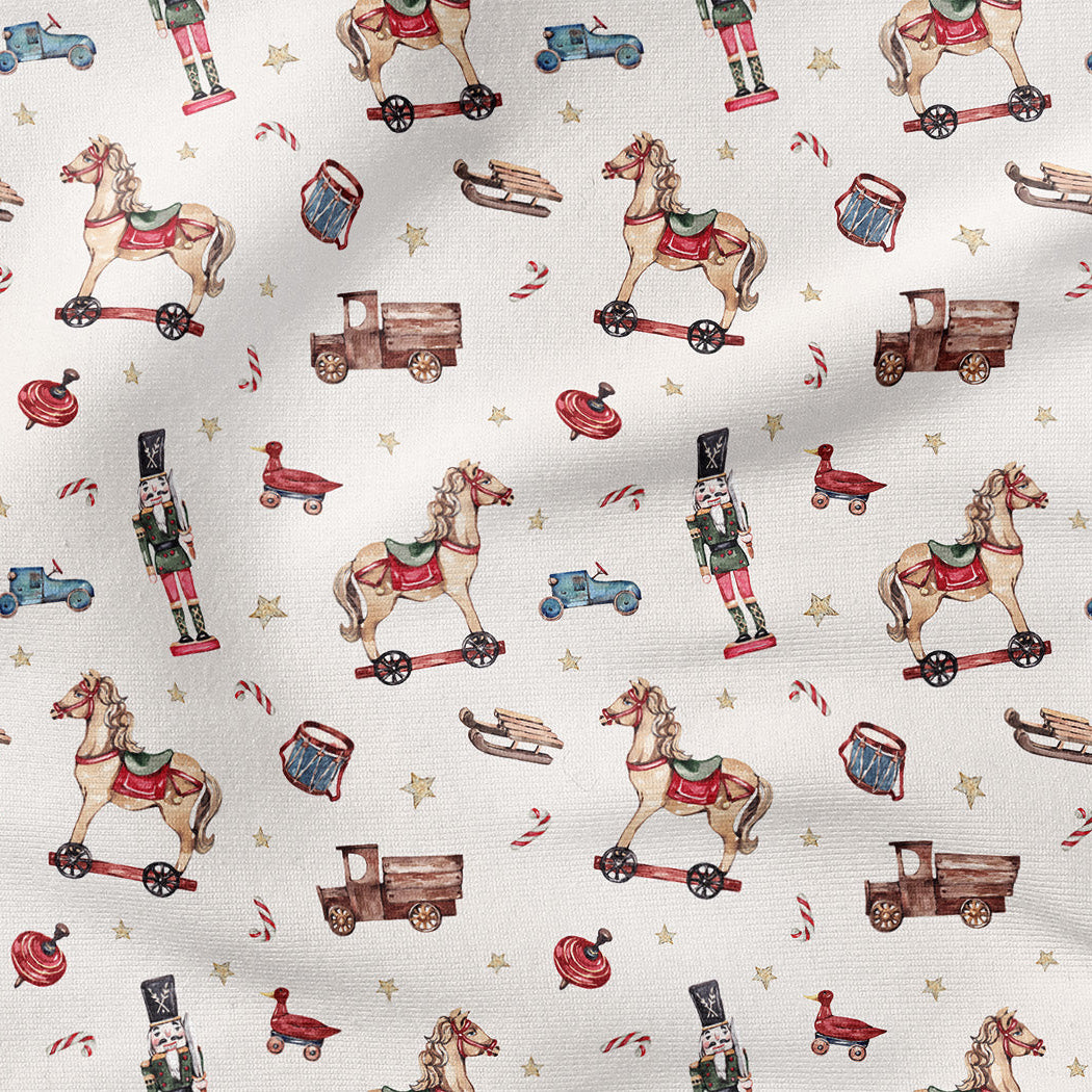 A close-up of a fabric pattern featuring vintage toy illustrations including rocking horses, toy trucks, nutcrackers, candy canes, and stars on an off-white background.