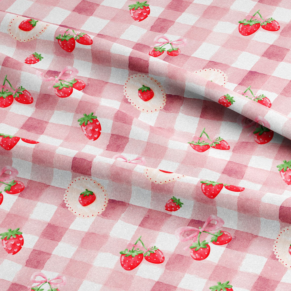 Pink and white gingham check fabric with a repeating pattern of red strawberries, green leaves, and small pink bows, shown folded to display the material and print.