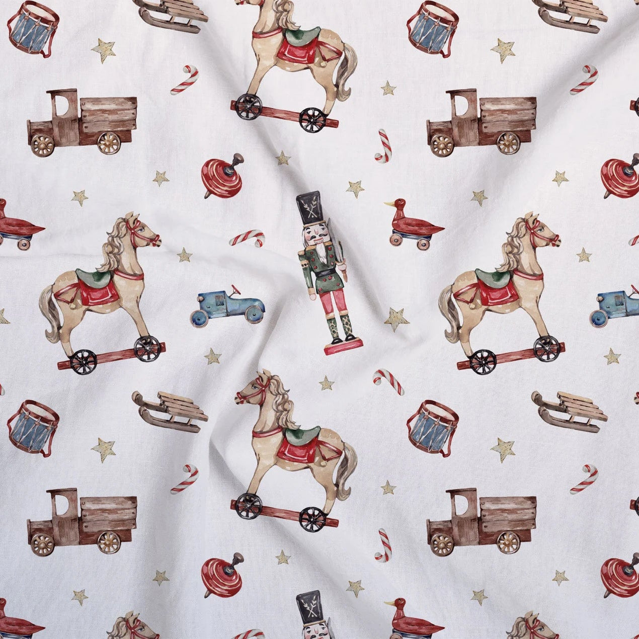 White fabric with a repeating pattern of vintage toy motifs including rocking horses on wheeled bases, nutcrackers, toy trucks, candy canes, sledding, and stars.