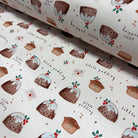 A close-up of a rolled piece of fabric or wallpaper featuring a repeating pattern of Christmas puddings, cups, and small handwritten text on an off-white background.