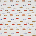 Close-up of white fabric with small, multicolored vehicle illustrations, perfect for kids' apparel and accessories