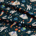 Space-themed fabric with astronauts, planets, and rockets on a dark blue background.