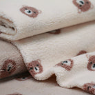 Repeated teddy bear face pattern on textured fabric