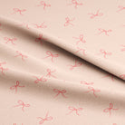 Pink bow pattern on beige fabric for arts and crafts