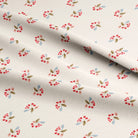 Floral patterned fabric with cherries and green leaves on a beige background