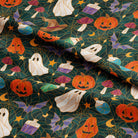 Halloween-themed fabric with a repeating pattern of orange jack-o'-lanterns, white ghosts, purple mushrooms, green bottles, yellow stars, and bats on a dark teal background.