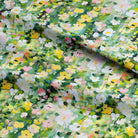 Floral fabric with a pattern of small flowers in green, yellow, and pink on a green background.