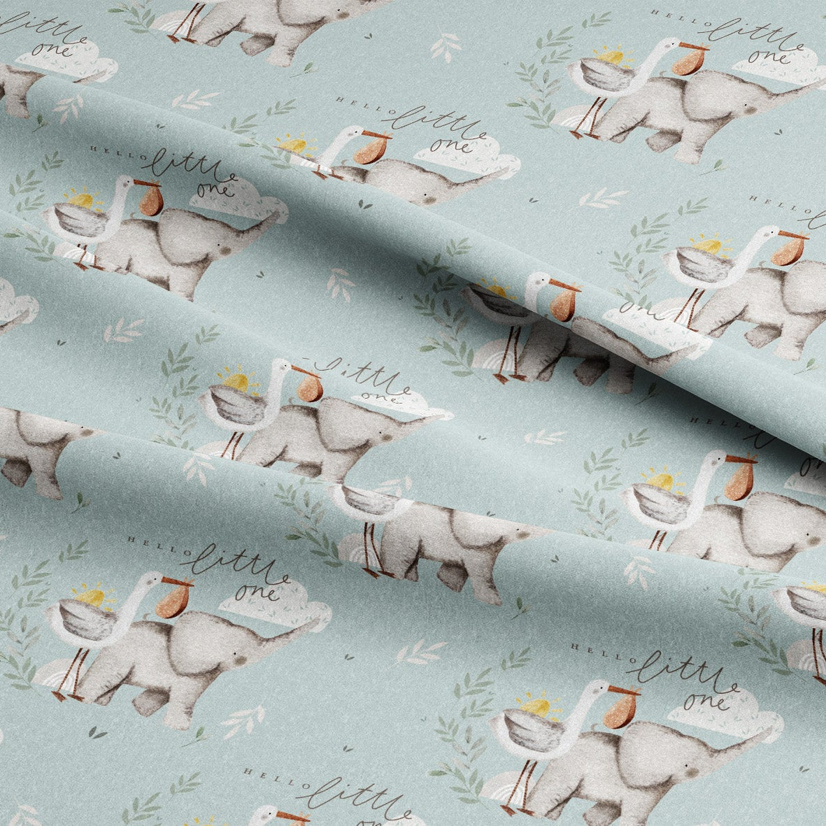 A close-up of a light blue fabric with a repeating pattern of white storks carrying baskets and the phrase 'little one' in script, with soft folds showing the material's texture.