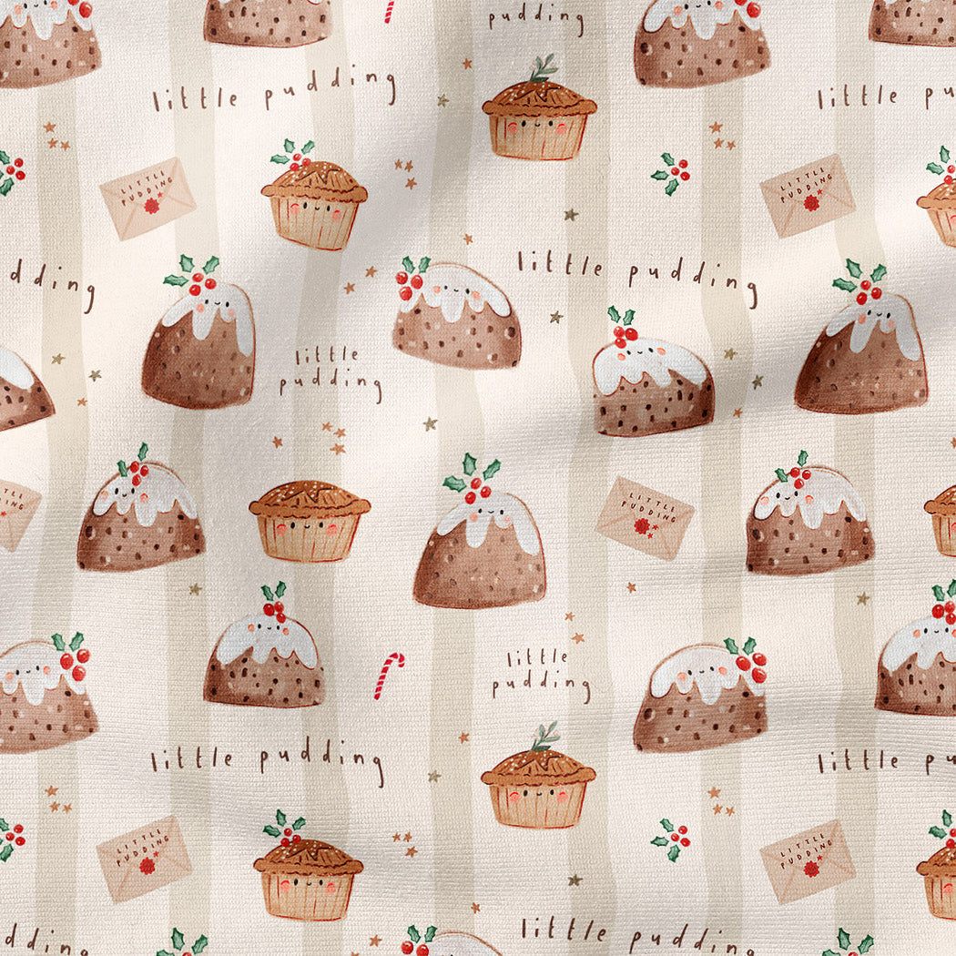 A close-up of a fabric or wallpaper pattern featuring illustrated Christmas puddings, cupcakes, candy canes, and the words 'little pudding' on a warm cream background.