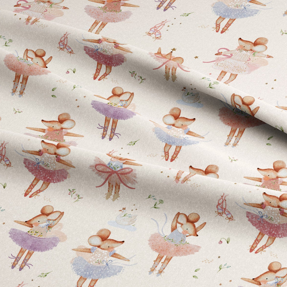 A close-up of a draped fabric featuring a repeating watercolor pattern of ballerina figures in pink, purple, and blue tutus on a warm cream background.