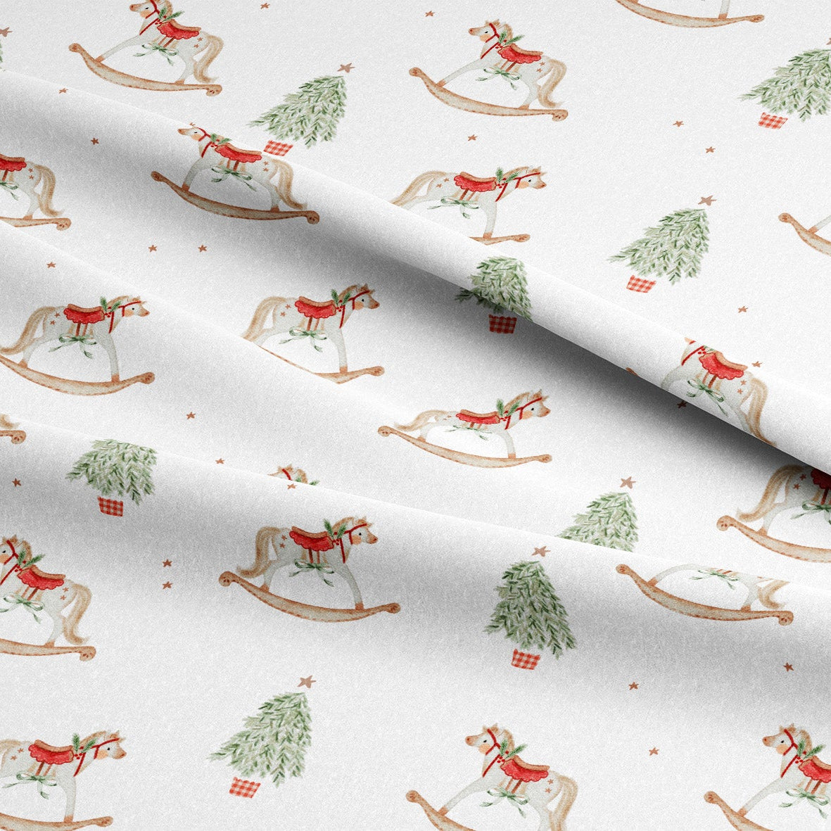White fabric with a repeating Christmas-themed pattern of rocking horses, green Christmas trees, and small red gift boxes, shown with a soft fold.