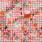 Red and white checkered fabric with autumn-themed illustrations including pumpkins, leaves, and animals.