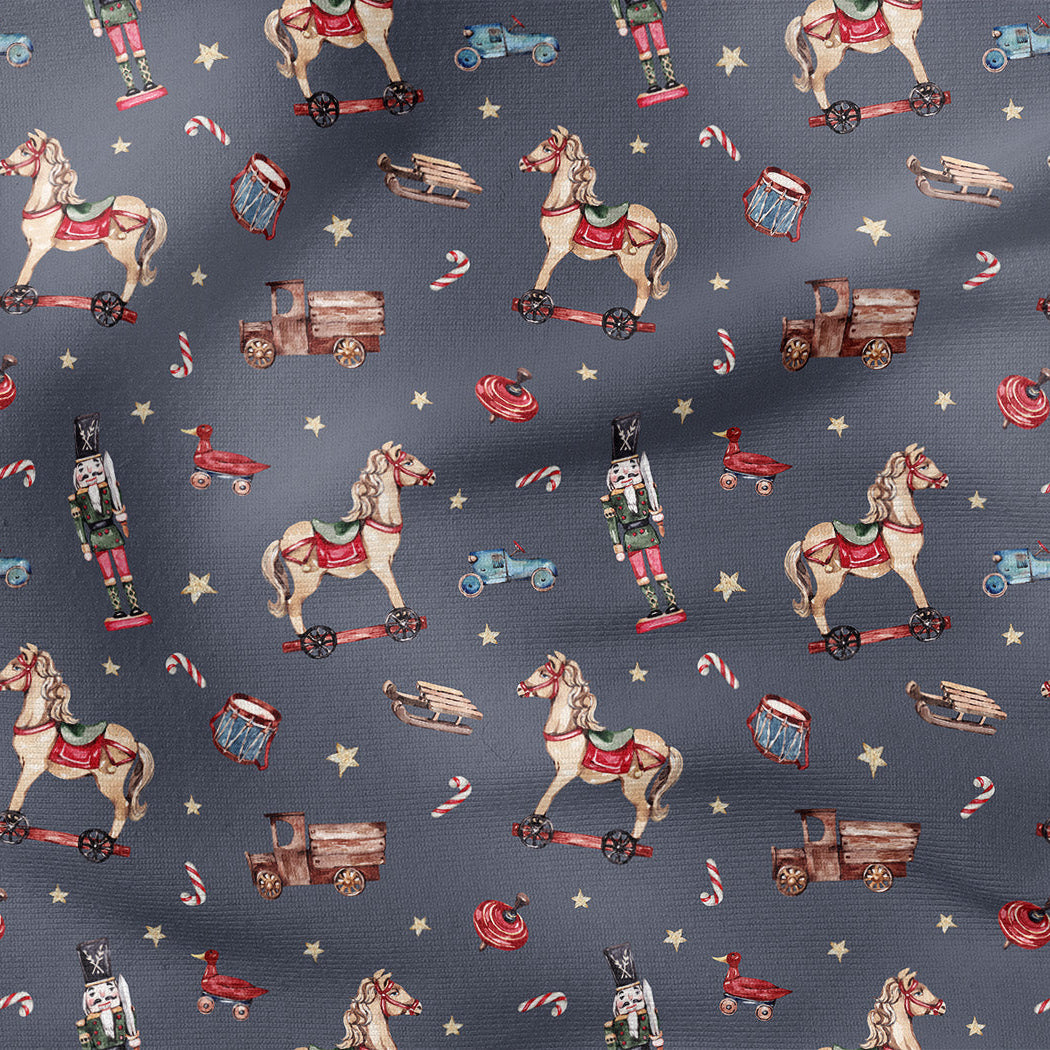 A close-up of a fabric pattern featuring vintage Christmas toys and candy cane motifs on a dark slate blue background.