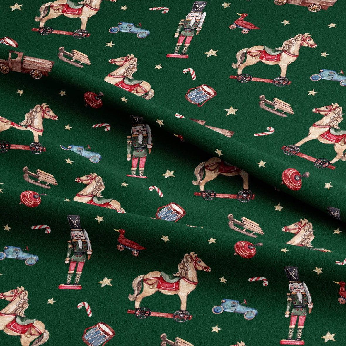 A close-up of dark green fabric printed with a holiday-themed pattern featuring toy horses, nutcrackers, candy canes, sleighs, and small vehicles, arranged in soft folds.