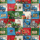 A repeating holiday-themed patchwork pattern featuring colorful toy delivery trucks, gift boxes, candy canes, snowflakes, and text labels such as 'Santa Crossing' and 'Toy Delivery' on red, green, blue, cream, and white squares.