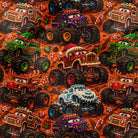 A close-up of a repeating pattern featuring colorful cartoon monster trucks on an orange background with candy cane motifs.