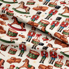 A close-up of a fabric or wallpaper pattern featuring a repeating design of classic Christmas toy motifs, including nutcrackers, rocking horses, toy trucks, and drums on an off-white background.
